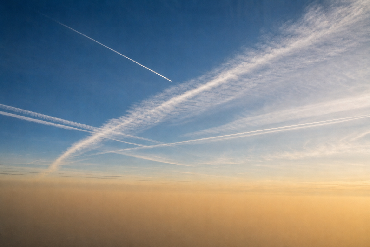 Illustrative editorial image of contrails spreading through a hazy Washington, DC-area sky